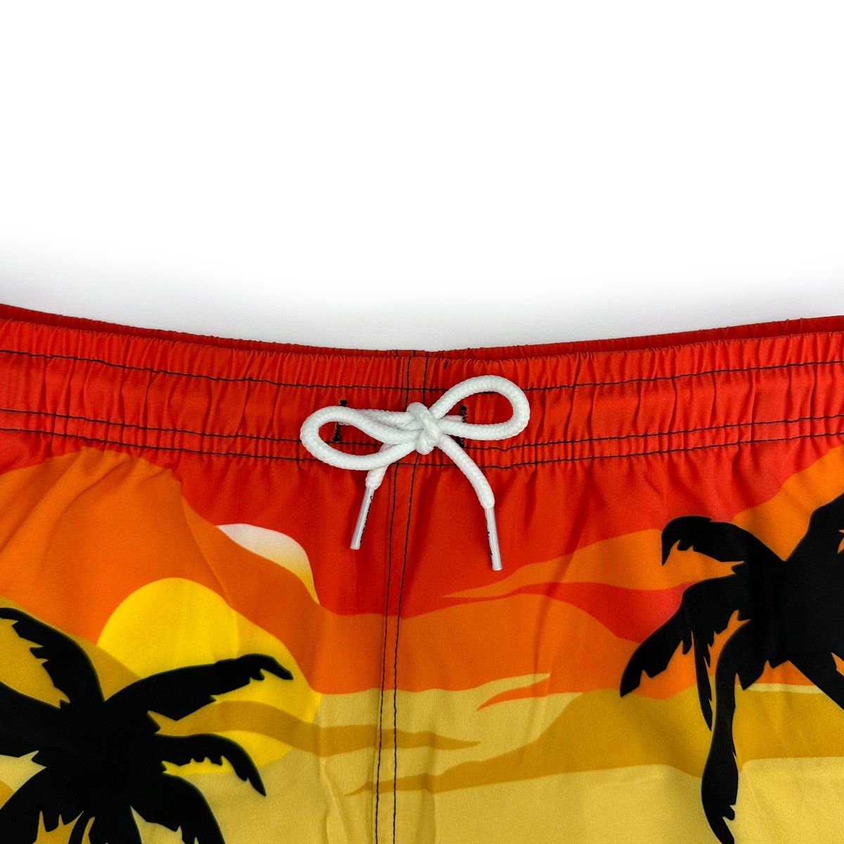 Close-up detail of elastic waistband and white drawstring on tropical sunset palm print boardshorts
