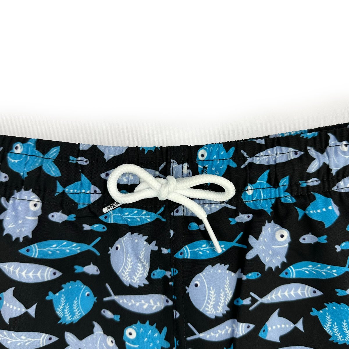Close-up detail of waistband stitching and tied drawcord on blue fish print swim trunks