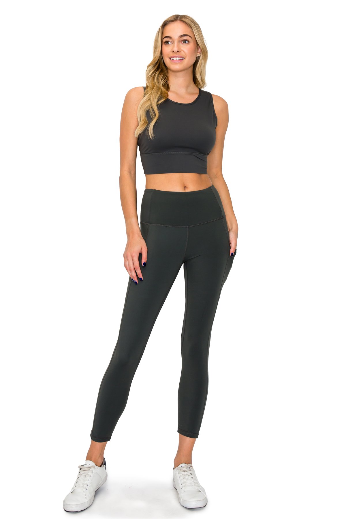 Model standing confidently in a dark charcoal grey leggings set with high waistband and side pocket details.