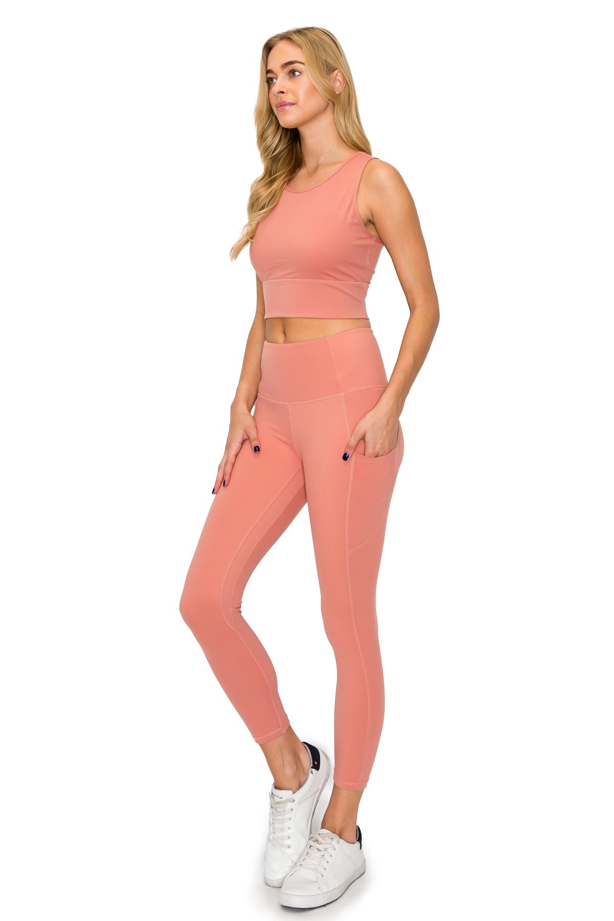 Blonde model posing in a dusty rose pink matching leggings set featuring deep side pockets.