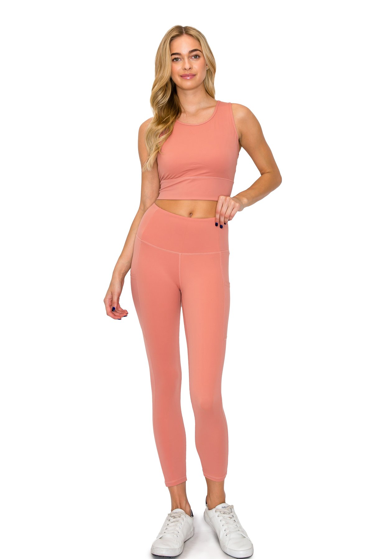 Blonde model wearing a dusty rose pink activewear set consisting of full-length leggings and a cropped top.